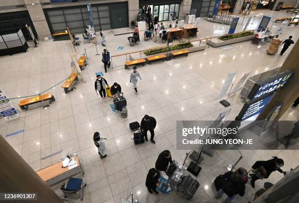 Staff members wearing protective equipment guide travellers at the arrival hall of Incheon International Airport on November 30 amid growing concerns...