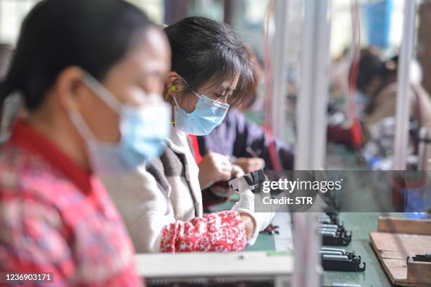 Women work on an assembly line producing speakers at a factory in Fuyang in China's eastern Anhui province on November 30, 2021. - China OUT / China...