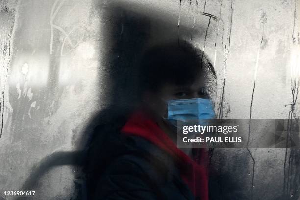 Commuter wearing a face mask rides a bus in Liverpool on November 30, 2021. - Britain will require all arriving passengers to isolate until they can...