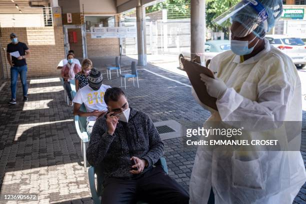 Healthcare worker helps a patient to fill out a form before conducting a PCR Covid-19 test at the Lancet laboratory in Johannesburg on November 30,...