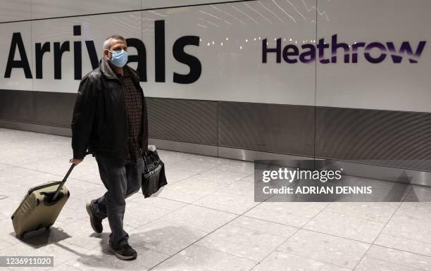 Man arrives at Heathrow's Terminal 5 in west London on November 30, 2021 as new restrictions on travellers are introduced. - All passengers entering...