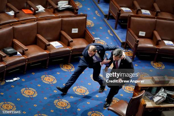 Member of the U.S. Capitol police rushes Rep. Dan Meuser out of the House Chamber as protesters try to enter the House Chamber during a joint session...