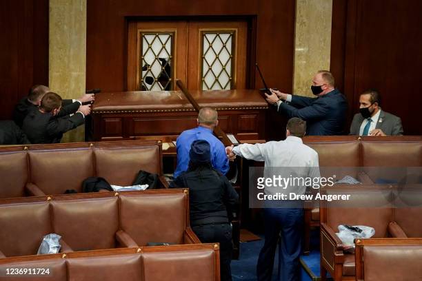 Law enforcement officers point their guns at the main door of the House Chamber as protestors attempt to enter the House Chamber during a joint...
