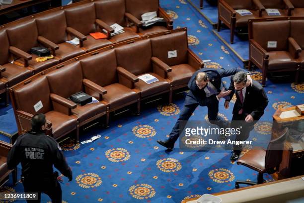 Member of the U.S. Capitol police rushes Rep. Dan Meuser out of the House Chamber as protesters try to enter the House Chamber during a joint session...