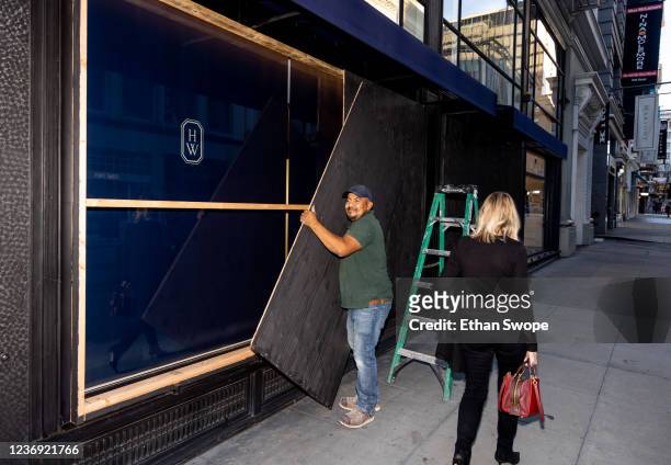 Raul Gomez removes wood paneling used to secure a store near Union Square on November 30, 2021 in San Francisco, California. Stores have increased...