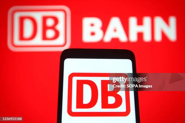 In this photo illustration, Deutsche Bahn AG logo is seen displayed on a smartphone and a pc screen.