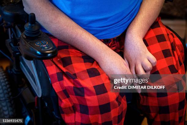 Daniil Maximov who lives with spinal muscular atrophy sits in a wheelchair in his apartment during an interview with AFP in Moscow on November 16,...