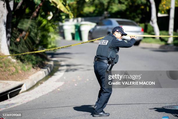 Police officer crosses under police tape as members of the media gather near the 1100 block of Maytor place where Jacqueline Avant's house is at the...
