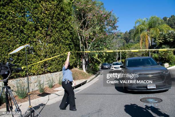 Police officer crosses under police tape as members of the media gather near the 1100 block of Maytor place where Jacqueline Avant's house is at the...