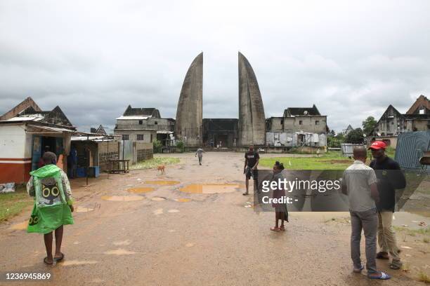 Residents walk in the open space in front of the silhouette of the Centre International des Civilisations Bantu with the two towers resembling...