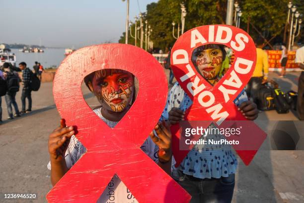 Two girls are seen with painted messages on their face holding a placard to raise awareness towards AIDS , during World AIDS day observation in...