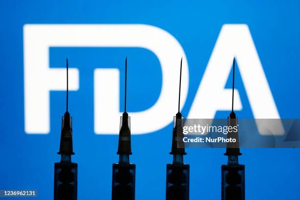 Medical syringes and FDA logo displayed in the background are seen in this illustration photo taken in Krakow, Poland on December 2, 2021.