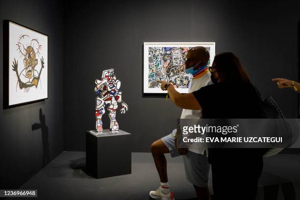 People look at artworks during the first day of the Art Basel 2021 exhibition at the Miami Beach Convention Center in Miami Beach, Florida, on...