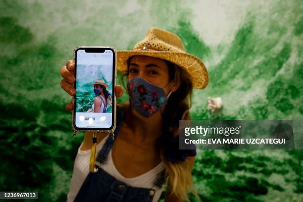 Woman shows a portrait of her in front of an artwork during Art Basel 2021 at Miami Beach Convention Center in Miami Beach, Florida on December 2,...