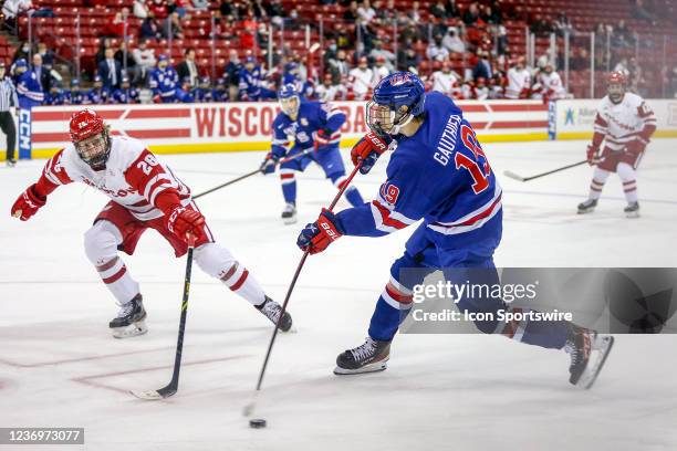 Wisconsin defenseman Shay Donovan tries to block a slap shot from U-18 forward Cutter Gauthier during a college hockey match between the University...