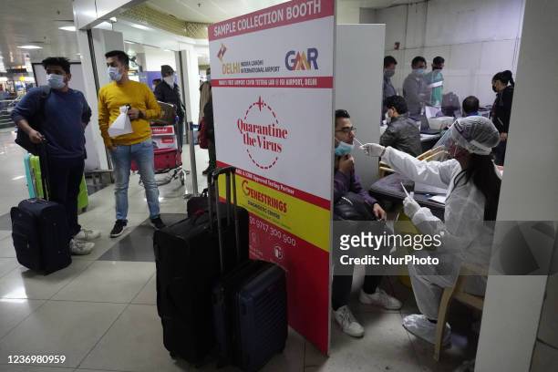 Healthcare worker collects a swab sample from a man to test for the coronavirus disease , at the Indira Gandhi International Airport in New Delhi,...