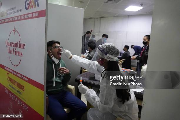 Healthcare worker collects a swab sample from a man to test for the coronavirus disease , at the Indira Gandhi International Airport in New Delhi,...
