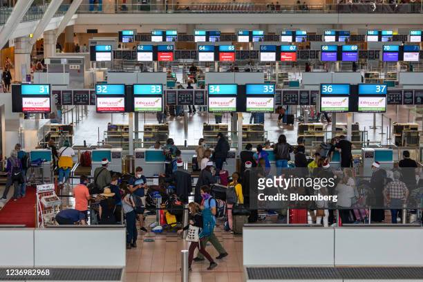 Passengers queue at check-in desks inside the departures terminal at Cape Town International Airport in Cape Town, South Africa, on Friday, Dec. 3,...