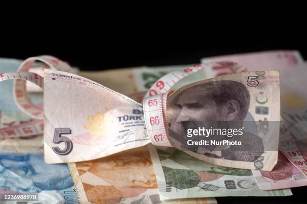 Photo Illustration of Turkish Lira banknotes in black background and a measuring tape as a symbol of the shrinking economy and currency. The lira...