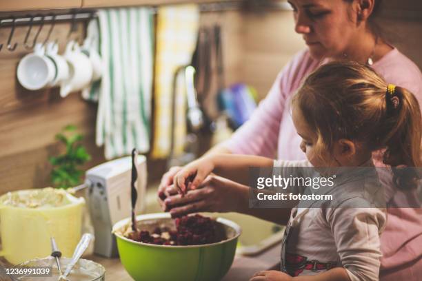 meisje dat kersen in het cakebeslag met haar moeder mengt - cheesecake white stockfoto's en -beelden