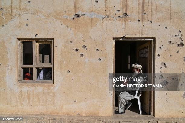 In this photograph taken on November 16 a teacher sits at the entrance of a classroom at a bullet riddled school in Arzo village on the outskirts of...