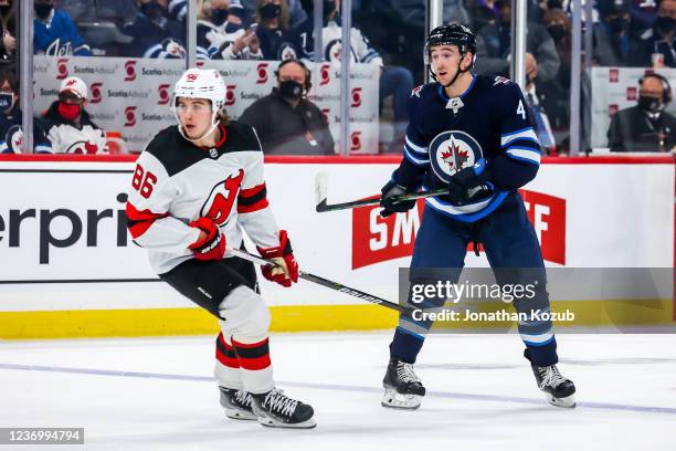 Jack Hughes of the New Jersey Devils and Neal Pionk of the Winnipeg Jets keep an eye on the play during second period action at the Canada Life...