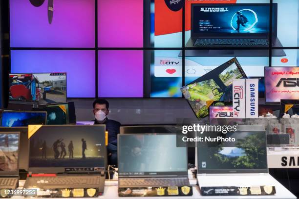 An Iranian salesman wearing a protective face mask looks on while sitting in an IT-City multi brand shop at the Paytakht computer centre in northern...