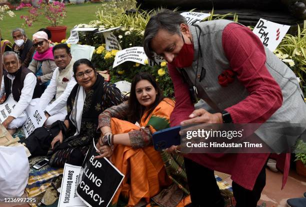 Suspended Rajya Sabha opposition MPs interact with Congress MP Shashi Tharoor during a protest near Mahatma Gandhi statue at Parliament House, on...