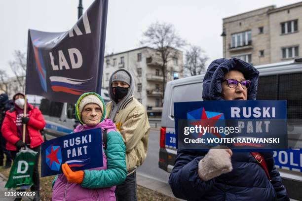 People hold signs reading "Russian Pact" as they protest in front of the venue where far-right party leaders including French Marine Le Pen of...