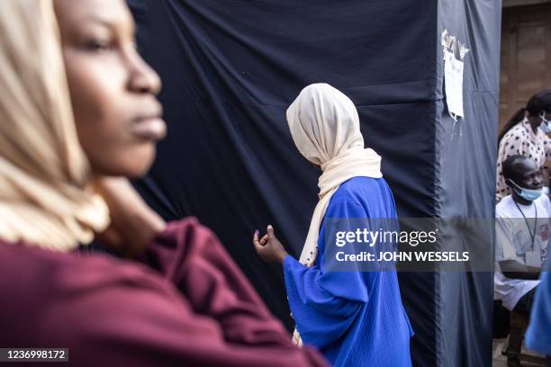 Woman enters a voting booth after the opening of a the vote in a market in the Manjai Kunda neighbourhood in Banjul on December 4, 2021. - Gambians...