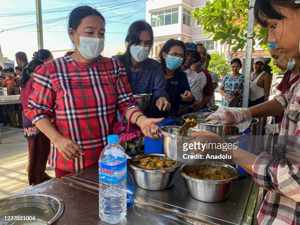 Volunteers serve meals into a steel bowl as people wait in line to get their turn for lunch in Yangon, Myanmar on November 30, 2021. "500MMK buffet...
