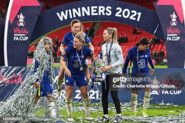 Millie Bright, Erin Cuthbert, goalkeeper Carly Telford and Sam Kerr of Chelsea wait to pose with the trophy as Ji So-Yun walks past covered in silver...