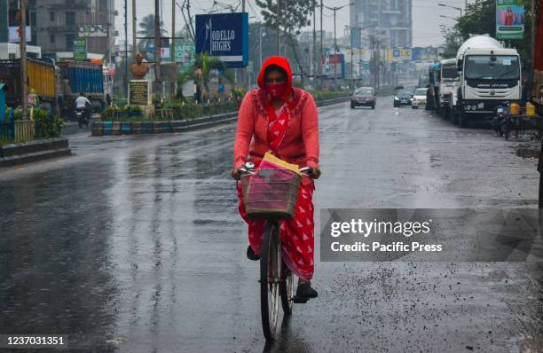 Woman wearing face mask riding on her bicycle during heavy rainfall due to Cyclone Jawad in Kolkata.