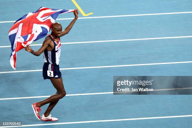 Mohamed Farah of Great Britain celebrates with his country's flag after claiming victory in the men's 5000 metres final during day nine of 13th IAAF...