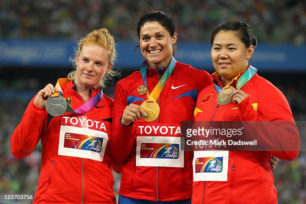Tatyana Lysenko of Russia celebrates with her gold medal, Betty Heidler of Germany her silver and Wenxiu Zhang of China her bronze in the medal...