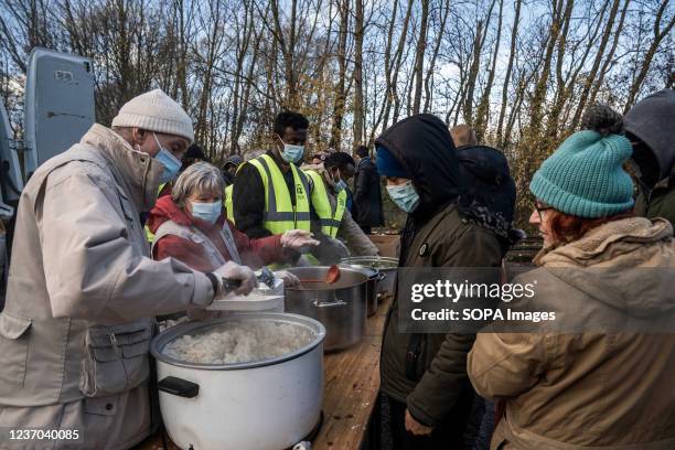 Volunteers of ADRA seen serving food to the migrants at a makeshift migrant camp. There are estimated around 800 migrants / refugees currently...