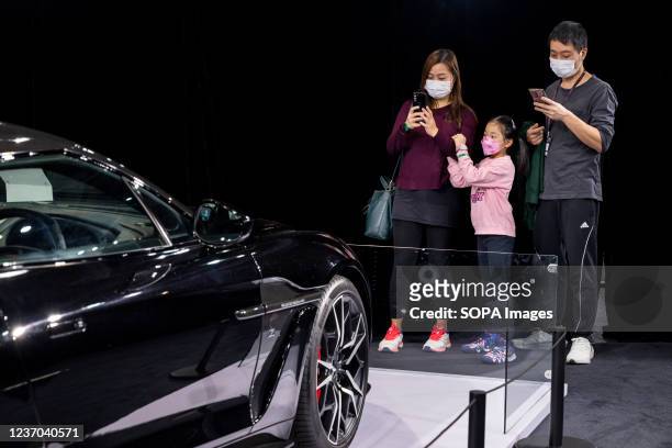 Family takes photo of an exclusive luxury sport car displayed during the International Motor Expo showcasing thermic and electric cars and...