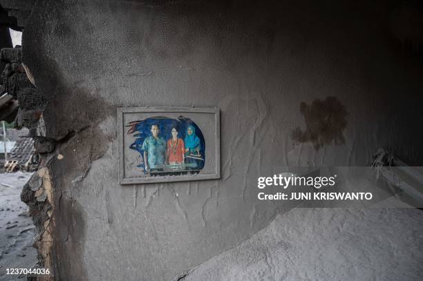 Family portrait still hangs in a damaged home at Sumber Wuluh village in Lumajang on December 6 following a volcanic eruption from Mount Semeru that...