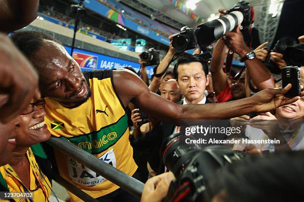 Usain Bolt of Jamaica celebrates victory and a new world record with his mother Jennifer Bolt following the men's 4x100 metres relay final during day...