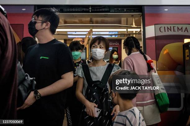 People wearing face masks exit a BTS skytrain in Bangkok on December 6, 2021 as Thailand recorded on Monday its first case of the Covid-19...