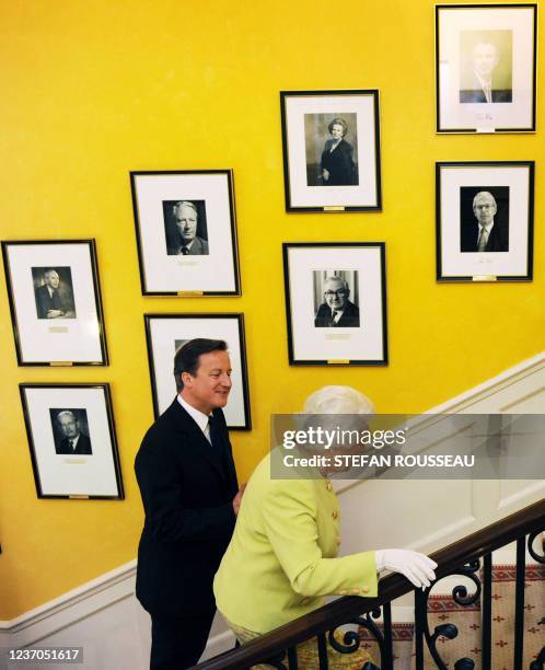 Britain's Queen Elizabeth II and British Prime Minister David Cameron walk up the stairs at 10 Downing Street, in central London, on June 21, 2011....