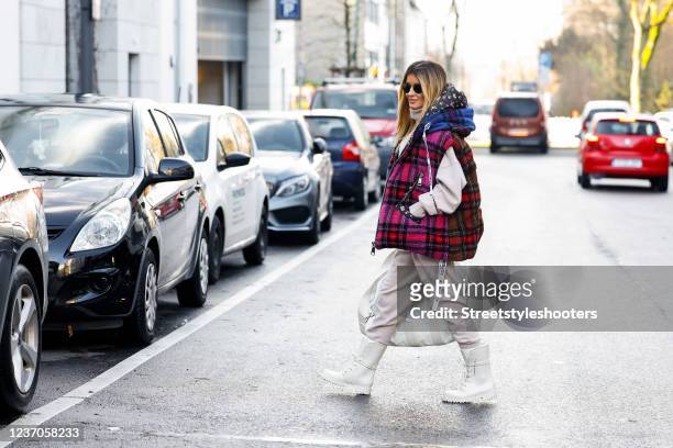 Influencer Gitta Banko wearing a multicolored plaid vest with floral lining by KhrisJoy, a beige turtleneck pullover by Extreme Cashmere, beige...