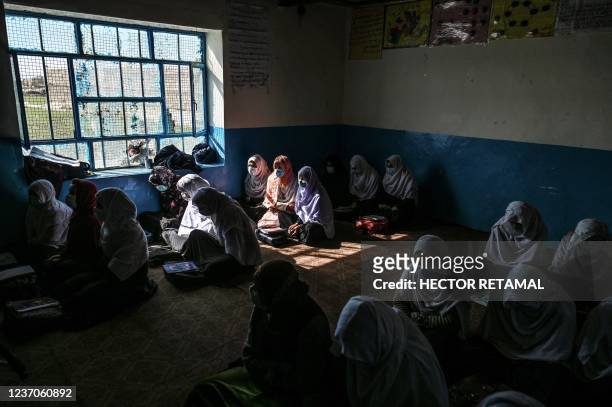 This picture taken on November 16, 2021 shows women sitting inside their classroom at Noorania school, in Sharan city, in the Paktika province. -...