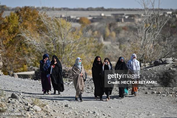 This picture taken on November 14, 2021 shows women going to back to their houses after attending a class of grade 12 in Langar village, in the...