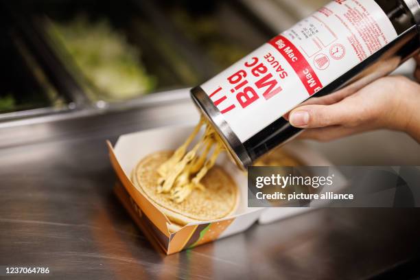 December 2021, Bavaria, Munich: An employee puts sauce on a burger while preparing a Big Mac at a branch of the McDonald's fast food chain in...