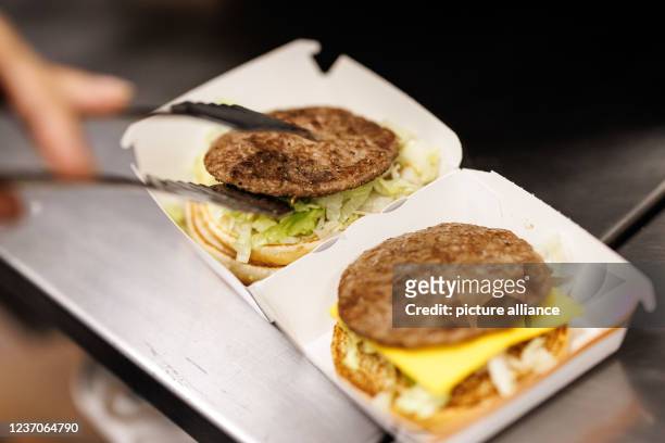 December 2021, Bavaria, Munich: An employee puts a patty on the burger while preparing a Big Mac at a branch of the McDonald's fast food chain in...