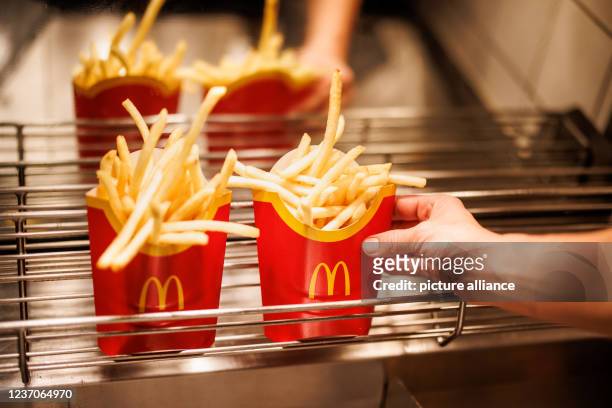 December 2021, Bavaria, Munich: An employee places a bag of French fries in a grid at a branch of the McDonald's fast food chain on...