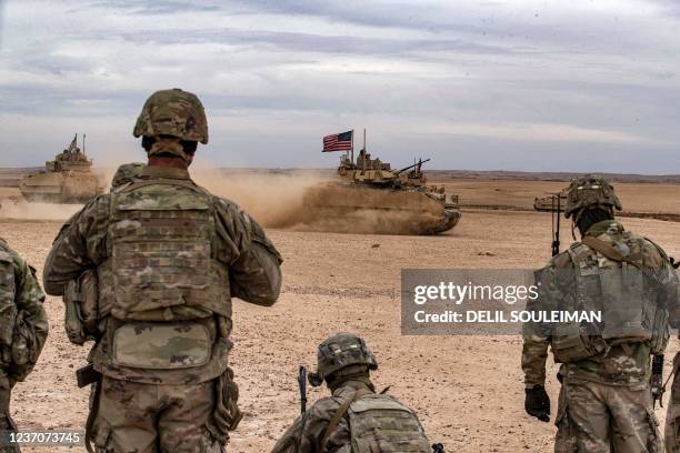 Soldiers watch as a US Bradley Fighting Vehicle drives during a joint military exercise between the Syrian Democratic Forces and the US-led...