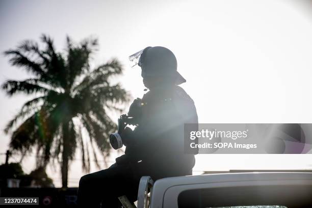 Policemen sits on back of a car during the protest. Supporters of the opposition United Democratic Party protest against the Gambia's presidential...