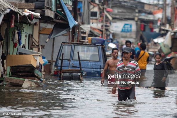 Residents wade through a flooded street by tidal waves in Jakarta's coastal area, Muara Angke, on Dec. 7, 2021. Local authorities predicted high...